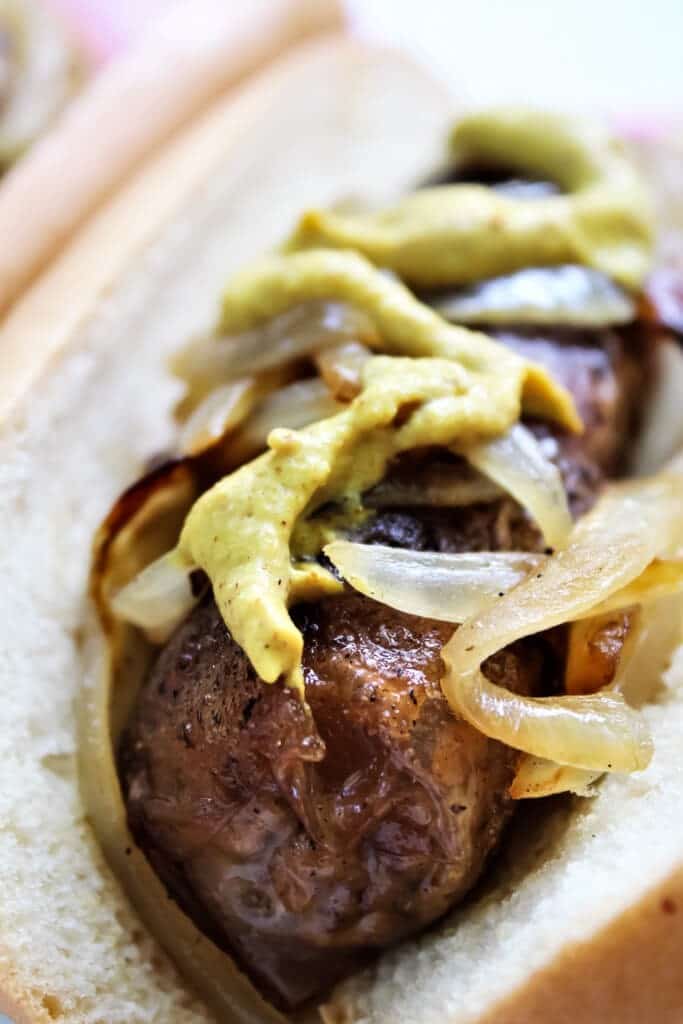 Salchicha de cerveza vegana con cebolla frita y mostaza.